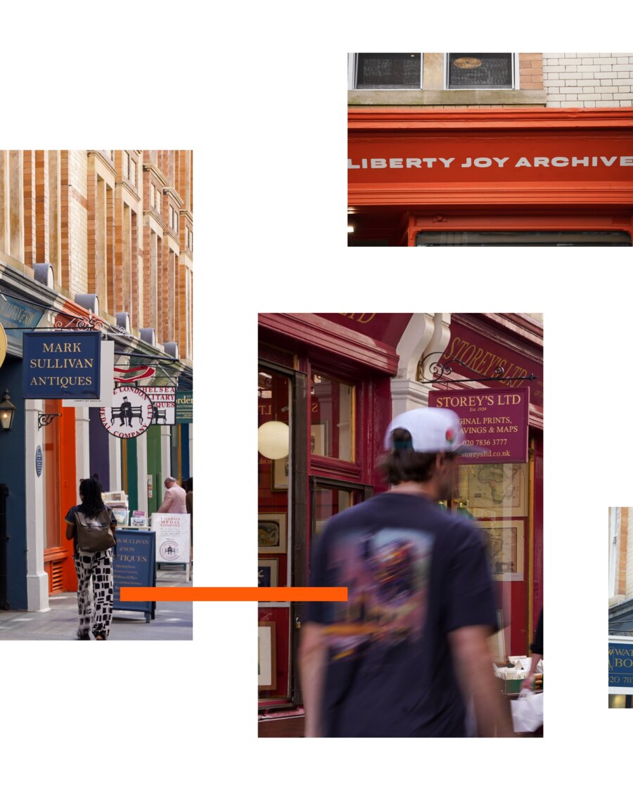 A view along Cecil Court past the red front of Storey&rsquo;s Ltd, hanging signs for Mark Sullivan Antiques receding down the row, and a man in a cap walking through the frame.